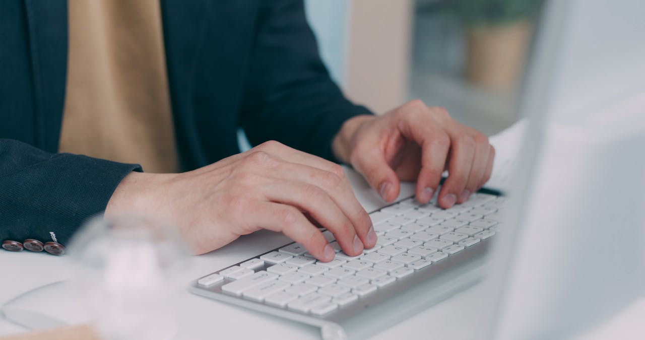 our-services-1 Close-up of hands typing on a white keyboard in an office setting. Ideal for business or technology themes.